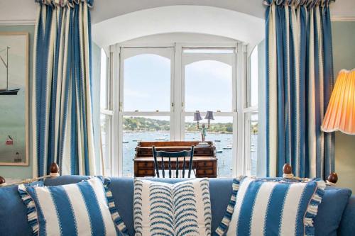 a living room with a blue couch in front of a window at Chy En Glas - By Rowes Retreats in Falmouth