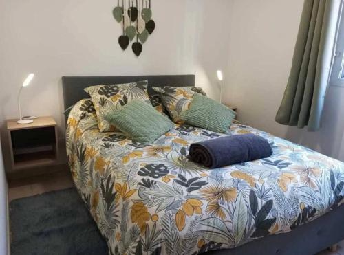 a bed with a flower patterned bedspread and pillows on it at L'Etoile Biterroise - Location appartement de vacances - Béziers in Béziers