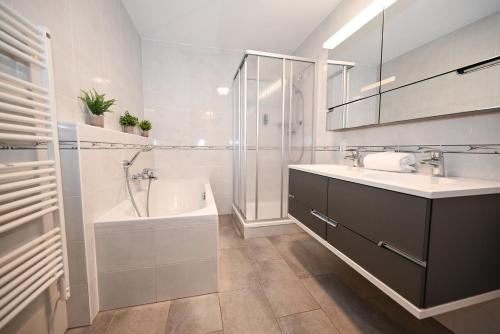 a bathroom with a sink and a tub and a shower at Schmitten Finest Apartments by All in One Apartments in Zell am See