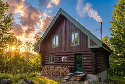 a tiny house in the woods with the sun setting at Le Bois Dormant - Spa, Fireplace, Pool, Lake, Tennis in Lac-Superieur