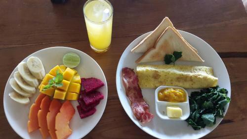 two plates of breakfast foods with a glass of orange juice at The Calmtree Bungalows in Canggu