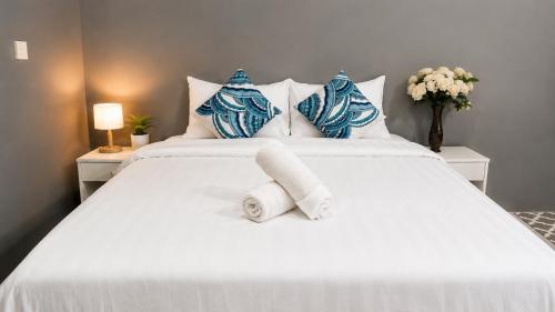 a white bed with blue and white pillows at Amazonite Maldives in Thulusdhoo