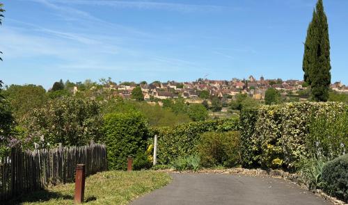 a road with a fence and a village in the distance at Le Clos Saint James 5 étoiles in Domme
