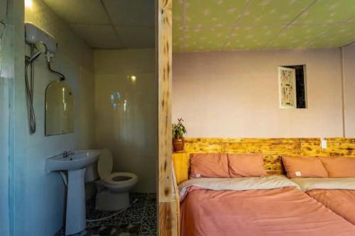 a bedroom with a bed and a sink and a toilet at Pine Aura Dalat Inn in Da Lat
