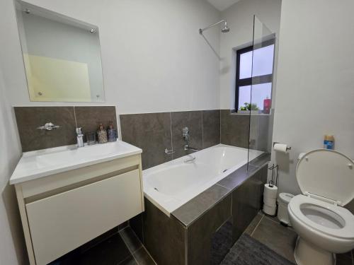 a bathroom with a tub and a toilet and a sink at Galani Homes Comfort 2-Bed Suite in Gaborone