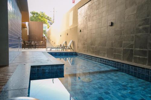 ein Schwimmbecken mit blauen Fliesen an der Seite eines Gebäudes in der Unterkunft HANNA Amsterdam Apart Hotel & Eventos in Florianópolis