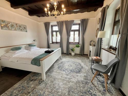 a bedroom with a white bed and a chair at Antik Vendégház in Nagyvisnyó