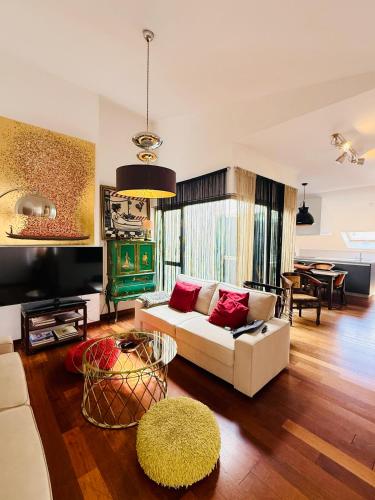 a living room with a white couch and a tv at Ático en Plaza de la Constitución 3 bedrooms in Málaga