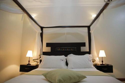 a bedroom with a large bed with two lamps at Esther properties in Entebbe