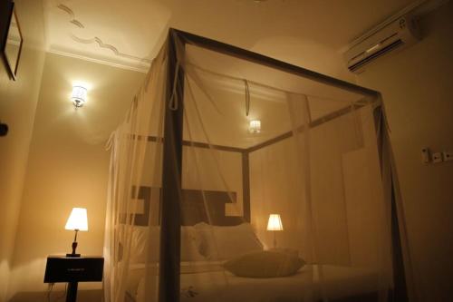 a bedroom with a canopy bed and a lamp at Esther properties in Entebbe