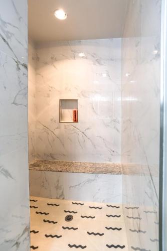 a bathroom with a shower with white marble walls at Private Luxury Pool House Retreat in Lake Charles