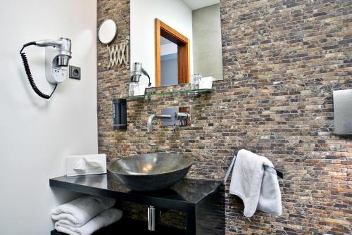 a bathroom with a sink and a brick wall at Ametyst Hotel Praha in Prague