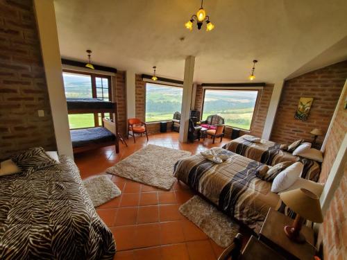 a bedroom with a bed and a couch and windows at Balcon al Cotopaxi Hosteria in Sangolquí