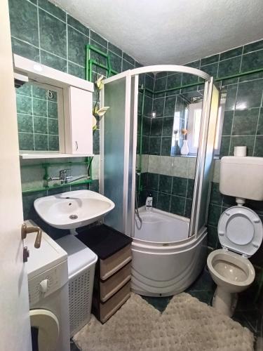 a green tiled bathroom with a toilet and a sink at Apartman Soldat in Šipovo