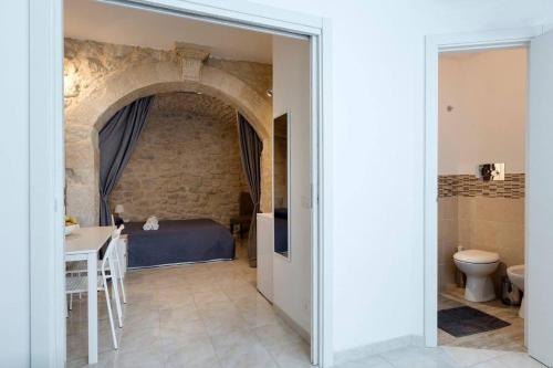 a room with a bed and a table and a bathroom at Casa Nerina in centro Scicli in Scicli