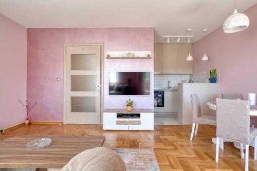 a living room with pink walls and a dining room at V&V apartment in Podgorica