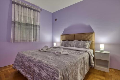 a bedroom with a large bed with purple walls at V&V apartment in Podgorica