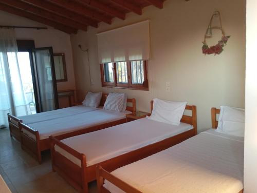 a room with three beds with white sheets at Avra Ηouse in Kriopigi