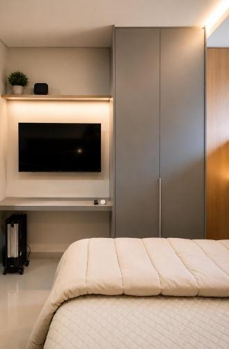 a bedroom with a flat screen tv and a bed at Studio Chico 02 in Espirito Santo Do Pinhal