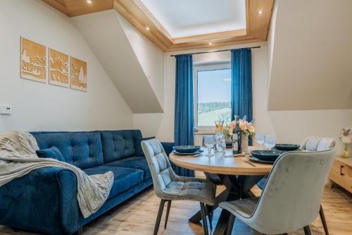 a living room with a blue couch and a table at Apartament Między Górami in Kacwin