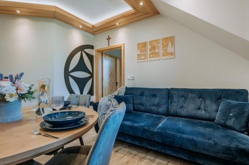 a living room with a blue couch and a table at Apartament Między Górami in Kacwin