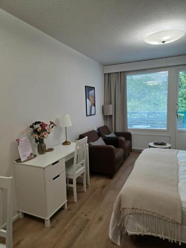a bedroom with a bed and a desk and a couch at Kylpylä-Hotelli 364 in Ikaalinen
