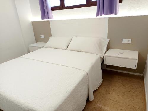 a small bedroom with two beds and a window at Teror Playa in Playa del Ingles