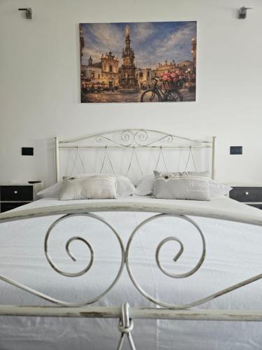 a bedroom with a white bed with a painting on the wall at B&B Helios in Nardò