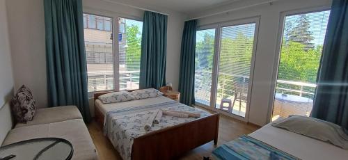 a bedroom with two beds and a couch and windows at Villa Bardha in Struga