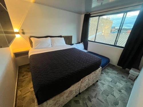 a bedroom with a bed and a large window at Hospedaje ZIG ZAG 2 in Tocancipá