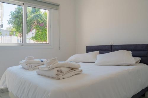 a white bed with towels on it with a window at BluWave Luxury Patio Spa Apartment Protaras Riviera in Paralimni