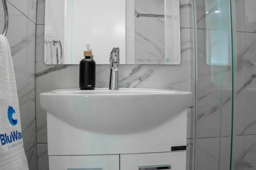 a bathroom sink with a black soap bottle on it at BluWave Luxury Patio Spa Apartment Protaras Riviera in Paralimni
