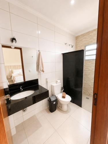a bathroom with a toilet and a sink and a mirror at Glória Hotel in Olímpia