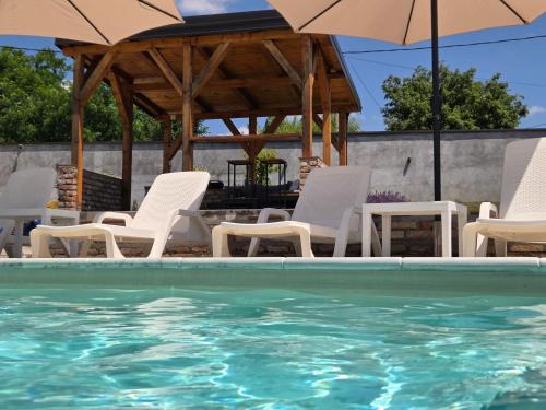 a group of chairs and umbrellas next to a swimming pool at Avalska Bajka in Ripanj