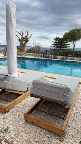 two beds sitting next to a swimming pool at ART BLUE Residence - Pool Access Apartment in Aghia Marina