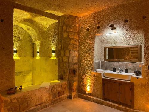 a stone bathroom with a sink and a tub and a sink at Masal Cave Suites - Where Story Begins in Ürgüp