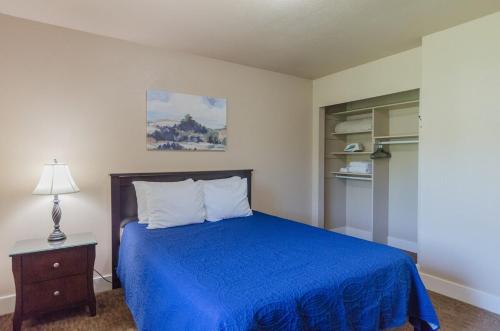 a bedroom with a blue bed with a nightstand and a lamp at Updated condo in Logan in Logan