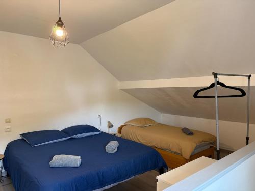 a bedroom with a blue bed in a attic at Charmante petite maison - 2 chambres in Homécourt