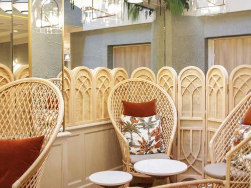 a row of wicker chairs and tables in a room at Mercure Paris Notre Dame Saint Germain des Prés in Paris