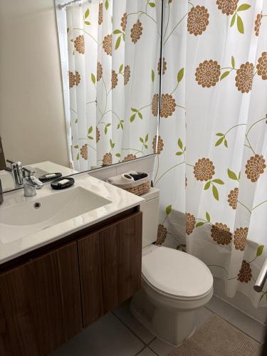 a bathroom with a toilet and a sink and a shower curtain at Comodo departamento 2 dormitorios con piscina in Quilpué