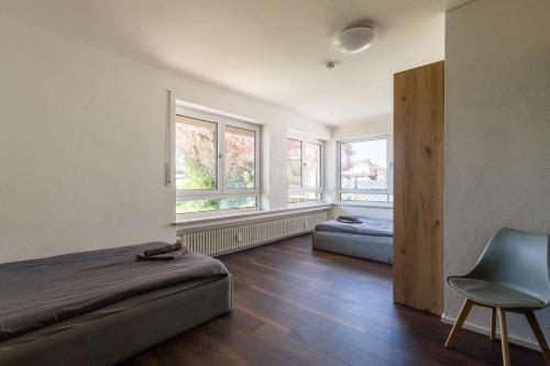 a bedroom with a bed and a chair and windows at 21 Pure relaxation Apartment in Memmingerberg