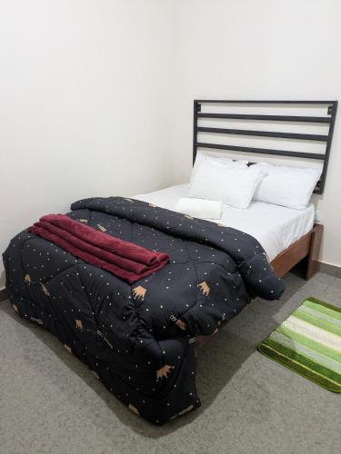 a bed with a black blanket and white pillows at Maneya Apartments in Kabwe