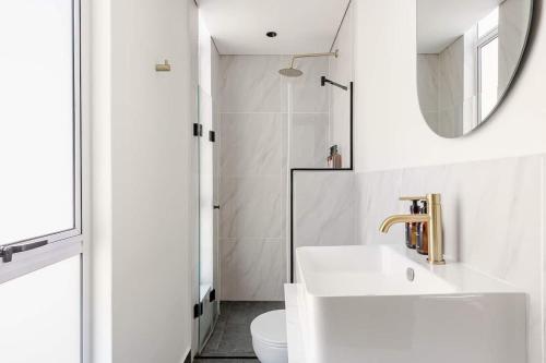 a white bathroom with a sink and a mirror at The Lookout in Cape Town