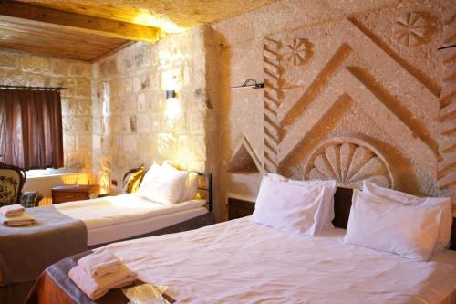 a bedroom with two beds and a stone wall at Masal Cave Suites - Where Story Begins in Ürgüp