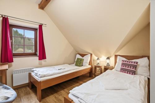 two beds in a attic room with red curtains at Chalupy Bret v Krkonoších- prostorná chalupa se 3 apartmány, se saunou nebo vířivkou in Žacléř