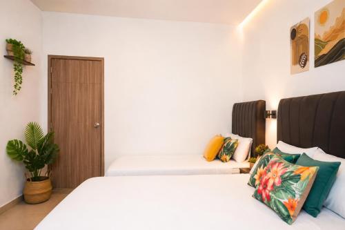 a bedroom with two white beds and a plant at CASTLE WHITE by MONARCA in Ríohacha