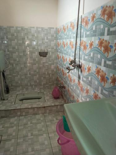 a bathroom with a tub and a tile wall at Hotel Ravi Park Lahore in Lahore