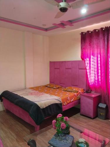 a bedroom with a pink bed and a table at Hotel Ravi Park Lahore in Lahore