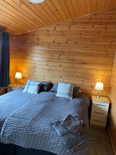 a bedroom with a bed in a wooden wall at Shepherds Lodge in Shiel Bridge