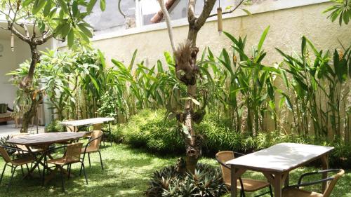 two tables and chairs in a garden with plants at Sugiras Living in Denpasar
